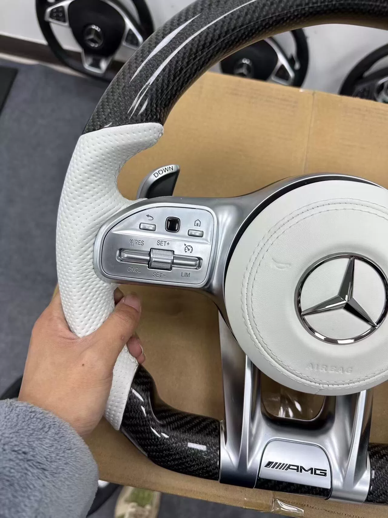 Mercedes-AMG Carbon Fiber Steering Wheel Assembly White perforated leather + black carbon fiber Features AMG badge / multi-function buttons / paddle shifters