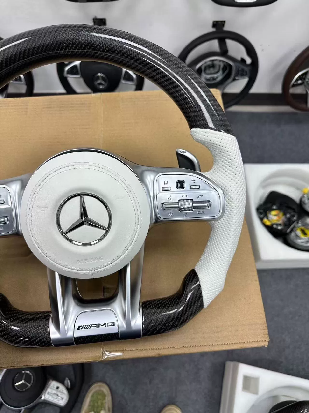 Mercedes-AMG Carbon Fiber Steering Wheel Assembly White perforated leather + black carbon fiber Features AMG badge / multi-function buttons / paddle shifters
