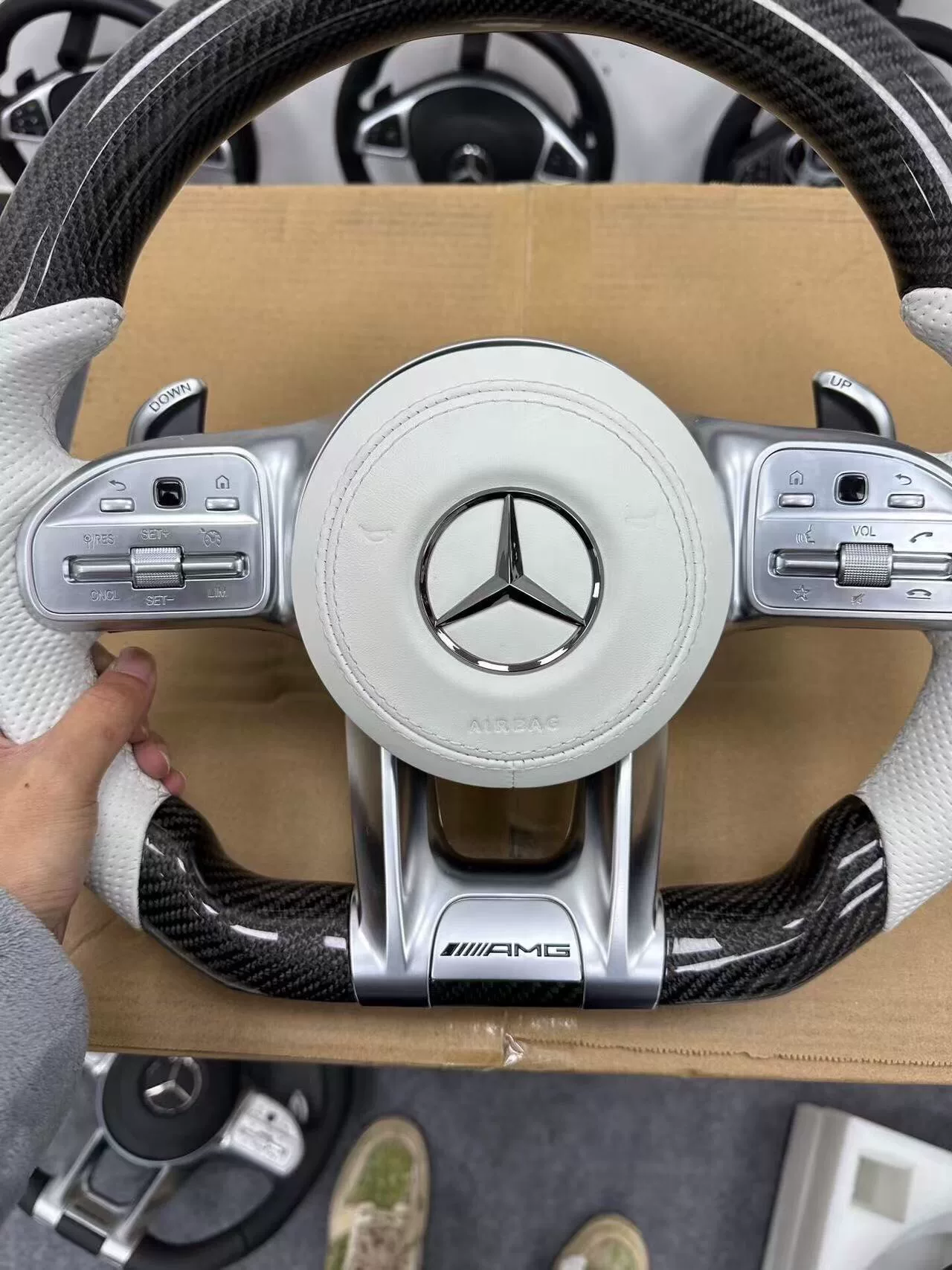 Mercedes-AMG Carbon Fiber Steering Wheel Assembly White perforated leather + black carbon fiber Features AMG badge / multi-function buttons / paddle shifters